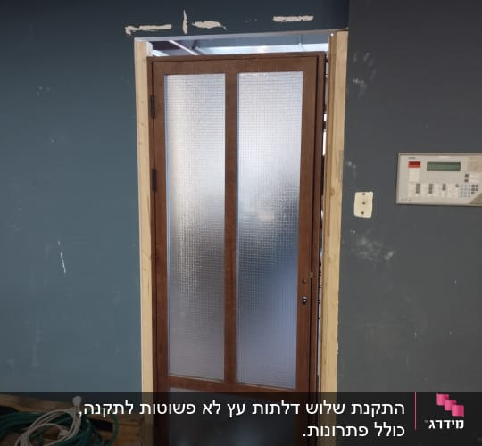 דלת עץ עם זכוכית מותקנת בקיר כחול